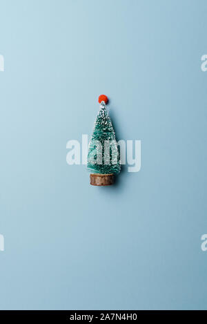 Miniature Christmas pine tree. Decorative Christmas tree on light blue background. Little snowy toy Christmas tree. Concept of New Year, Christmas hol Stock Photo