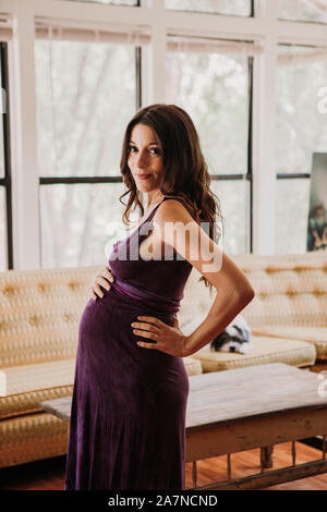 Pregnant woman stands in her living room Stock Photo