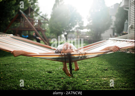 Joyful girl 10-12 years old swinging and laughing in hammock outside Stock Photo