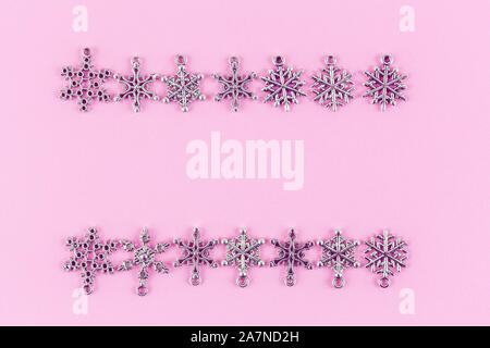 Two rows of silver snowflakes with text space between them on pink background - christmas holidays theme Stock Photo
