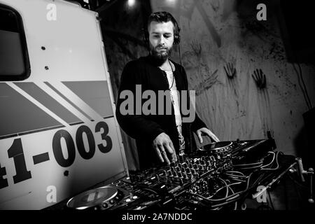 KHARKIV, UKRAINE - OCTOBER 26, 2019: DJ plays live set and mixing music on turntable console at stage in the night club. Disc Jokey Hands on a sound Stock Photo