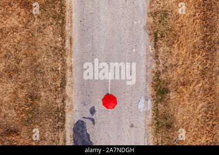 Red umbrella on road, top view from drone pov Stock Photo