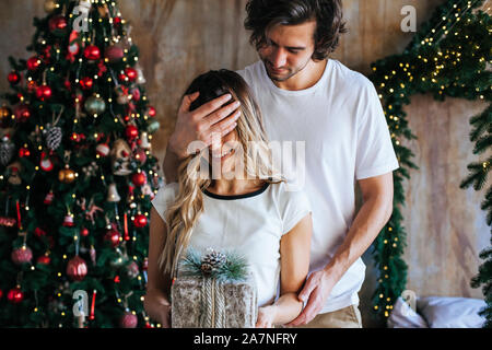 Young man hugging a young woman holding a wrapped gift box Stock Photo