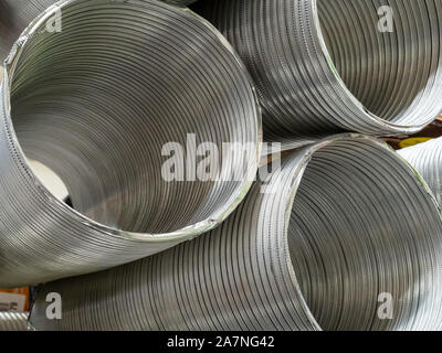 Aluminum duct sections sitting on top of each other in indoor storage area Stock Photo