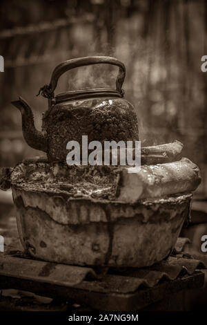 An old water kettle in use on the top of the firewood Stock Photo