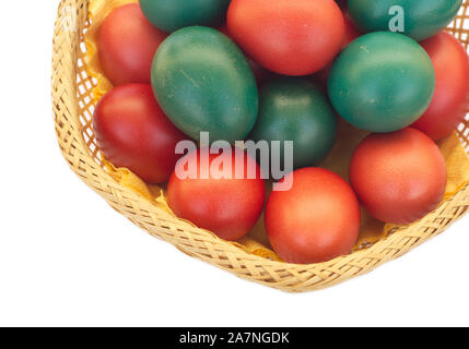 Colored Easter eggs in brown straw bowl isolated on white background Stock Photo