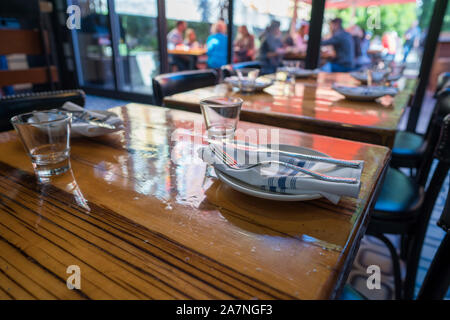 Table setting of cups, napkins, plates, and utensils in casual restaurant Stock Photo
