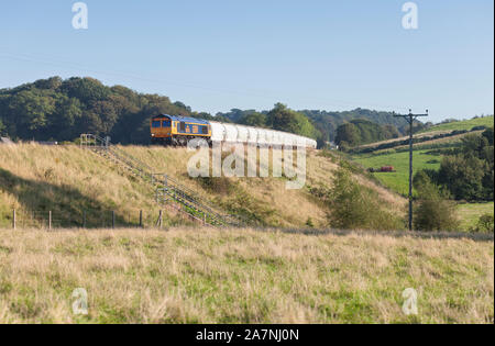 GB railfreight class 66 diesel locomotive passing How on the Tyne valley railway line in Cumbria with a freight train carrying bulk alumina