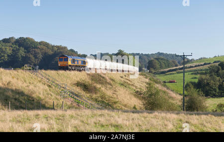 GB railfreight class 66 diesel locomotive passing How on the Tyne valley railway line in Cumbria with a freight train carrying bulk alumina