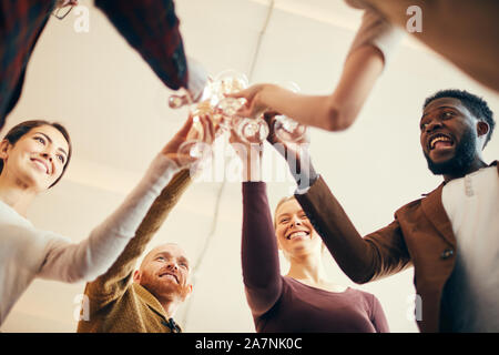 Low angle view at group of elegant people clinking champagne glasses during party at work, copy space Stock Photo