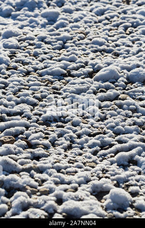 Snow and icy texture from fresh snowfall on a river bank and rocks Stock Photo