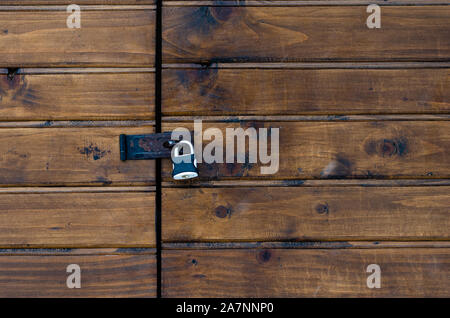 Closed padlock on a painted brown pine wooden door Stock Photo