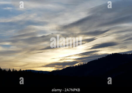 Cloudy  dramatic sky over silhouette landscape during winter at sunset Stock Photo