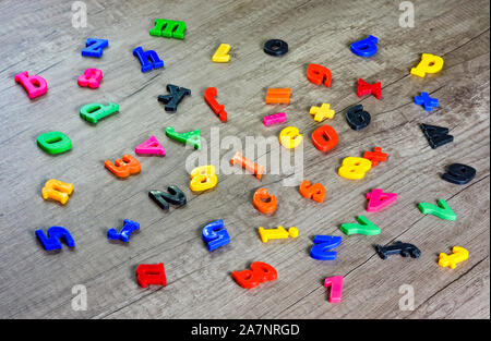 Close up  shot of multi colored  plastic toy  numbers and  letters on  wooden table . Stock Photo