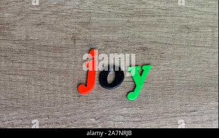Joy    word  written with  plastic  multi colored  letters on a wooden table . Stock Photo