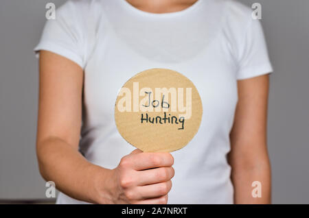 Women hand   holding    round cardboard paper     with handwritten advertisement   text  - Job Hunting. Stock Photo