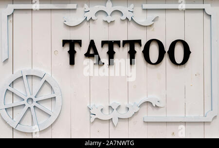 The word tattoo written with black wooden letters on a white board background as an advertisement for those who want to get a tattoo Stock Photo