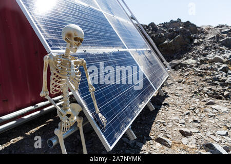 Skeleton leaning on solar panels in the desert Stock Photo