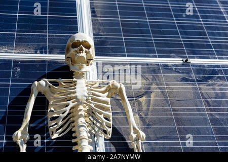 Skeleton leaning on solar panels in the desert Stock Photo