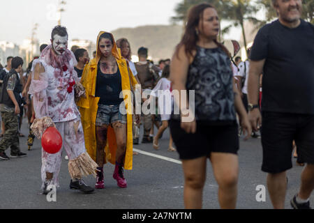 Halloween walk of zombies on the Day of the Dead, Finados, in Copacabana with a female disfigured zombie and palm trees and beach in the background Stock Photo