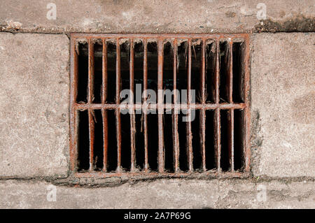 Old rusty ruin metal sewage grate dirty iron drainage cover on city street top view Stock Photo
