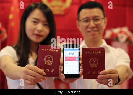 A couple shows their marriage certificates and digital marriage certificate on their smartphone at a civil affairs office on the traditional Chinese f Stock Photo