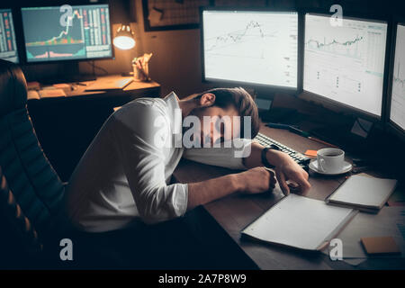 Young male trader at office work concept sitting sleeping. Stock Photo