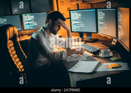 Young male trader at office work concept sitting tired. Stock Photo