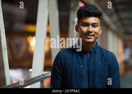 Face of happy young Asian man smiling on the footbridge at night Stock Photo