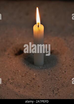 Lit Candle In Sand Stock Photo