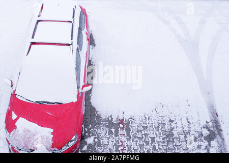 A red car is parked in the snow. Snowfall. Winter season.Car under snow in winter Stock Photo