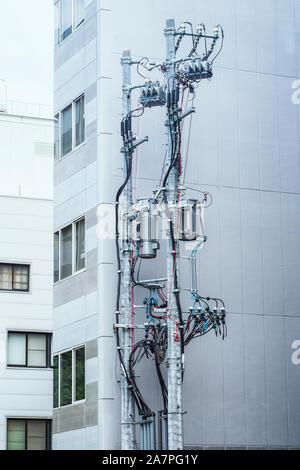 Modern poles with electricity cables on the background of a residential building, poles with electric wires, telecommunication pole .background. Stock Photo