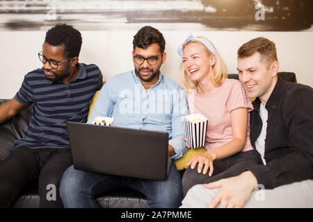 Happy diverse friends students group looking at laptop having fun watching comedy movie, online show, funny video. Multiracial young people laughing u Stock Photo