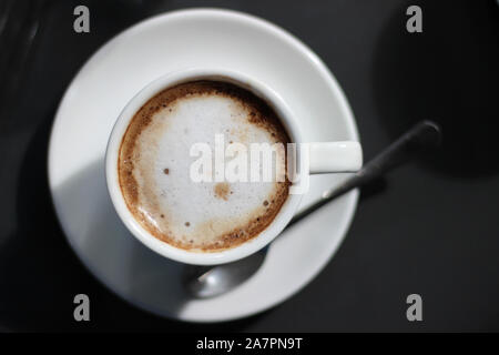 Top View of Cappuccino in Demitasse Cup. Overhead view of Coffee on the Dark Background. Stock Photo