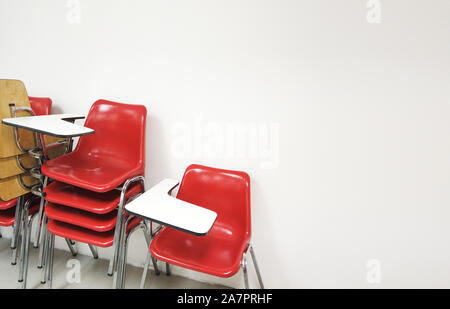 Red plastic folding chair stack on classroom background. Stock Photo