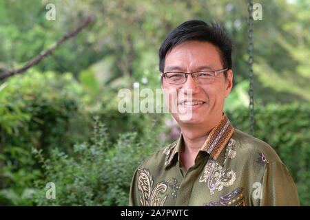 Portrait of an Asian Chinese successful businessman in formal traditional batik shirt, smiling at the camera. Confident. Stock Photo