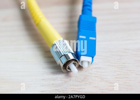 close-up single cable fiber optical connector ST-type on wood table Stock Photo