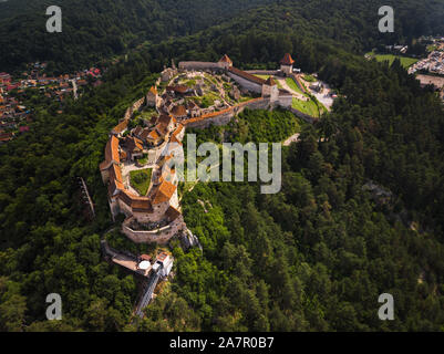Aerial footage of Rasnov castle from above during a clear summer day with lush orange roofs and green forest (Rasnov, Romania, Europe) Stock Photo