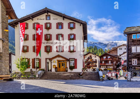 Zermatt, Switzerland - October 7, 2019: Town main street view in famous swiss ski resort, Gemeindehaus, mountains and people Stock Photo