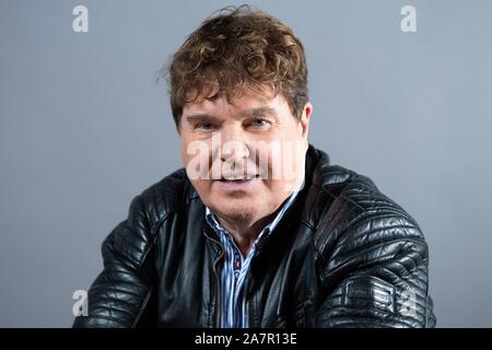 Dresden, Germany. 30th Oct, 2019. The singer Frank Schöbel sits in front of a photo wall in the boulevard theatre. The occasion is the presentation of the musical 'Frank Schöbel Story', which deals with the career of the GDR hit singer Frank Schöbel on stage. Credit: Sebastian Kahnert/dpa-Zentralbild/dpa/Alamy Live News Stock Photo