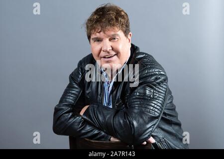 Dresden, Germany. 30th Oct, 2019. The singer Frank Schöbel sits in front of a photo wall in the boulevard theatre. The occasion is the presentation of the musical 'Frank Schöbel Story', which deals with the career of the GDR hit singer Frank Schöbel on stage. Credit: Sebastian Kahnert/dpa-Zentralbild/dpa/Alamy Live News Stock Photo