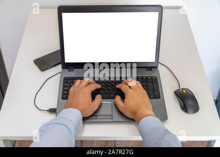 Person working on a laptop in a business office enviroment. Over the shoulder shot of man typing on a computer with blank screen. Stock Photo