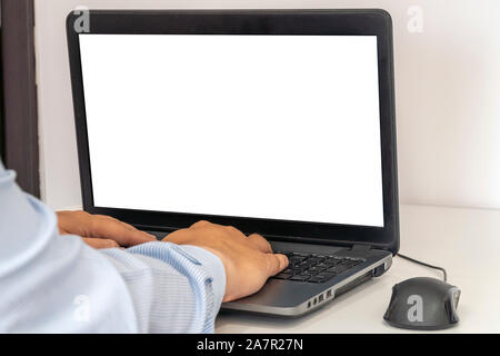 Person working on a laptop in a business office enviroment. Over the shoulder shot of man typing on a computer with blank screen. Stock Photo