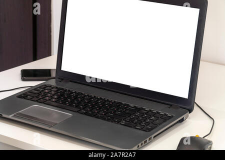 Person working on a laptop in a business office enviroment. Over the shoulder shot of man typing on a computer with blank screen. Stock Photo