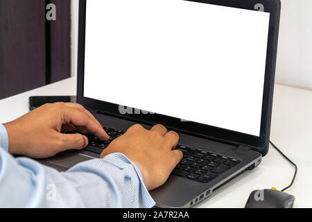 Person working on a laptop in a business office enviroment. Over the shoulder shot of man typing on a computer with blank screen. Stock Photo