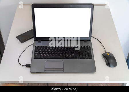 Person working on a laptop in a business office enviroment. Over the shoulder shot of man typing on a computer with blank screen. Stock Photo