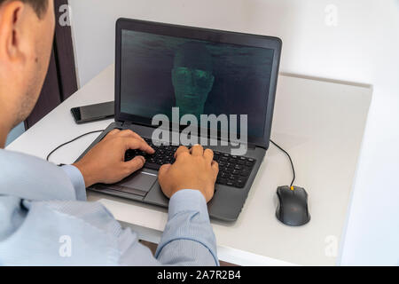 Developer coding on a laptop and creating a artificial intelligence software. Human like face made out of code appearing on the screen. Stock Photo