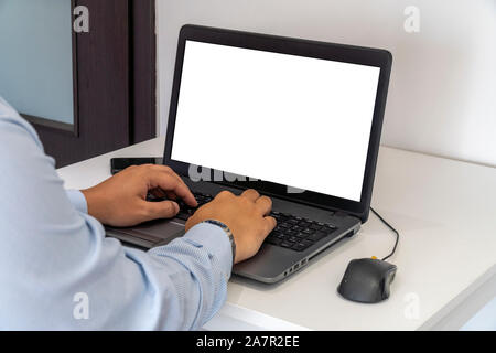 Person working on a laptop in a business office enviroment. Over the shoulder shot of man typing on a computer with blank screen. Stock Photo