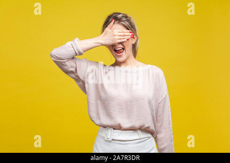 Portrait of confused, shocked or scared woman with fair hair in blouse standing, covering her eyes, don't want to watch. fear or shame expression. ind Stock Photo