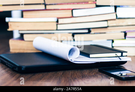 Open textbook, notebook, smartphone, laptop computer, stack of books education back to school background, paperweight, documents, glasses and pencils Stock Photo